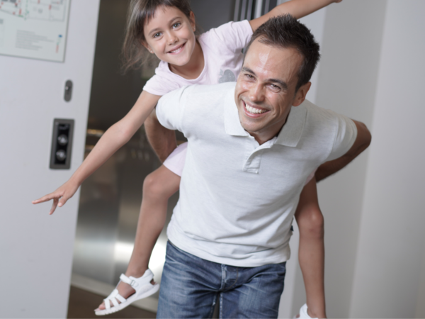 Padre con figlia alle spalle mentre esce da un ascensore Orona